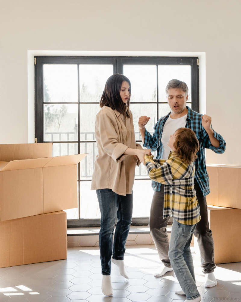 Frau, Mann und Kind feiern den Einzug in ein getauschtes Eigenheim.